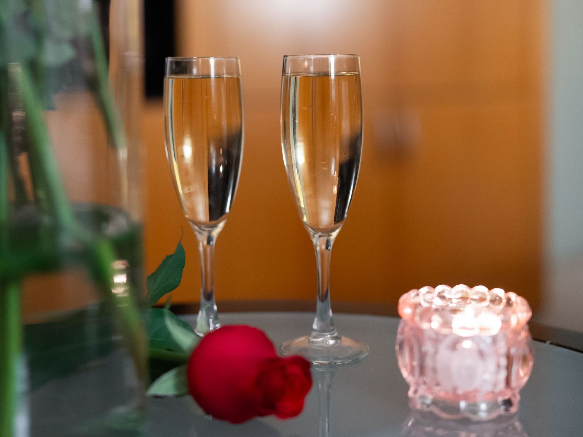 Dos copas de champán y una rosa sobre una mesa.