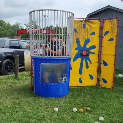 A man is sitting in a dunk tank with a yellow wall behind him