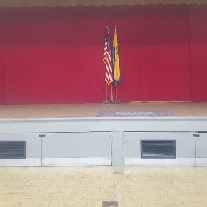 An empty stage with two flags on it and a red curtain.