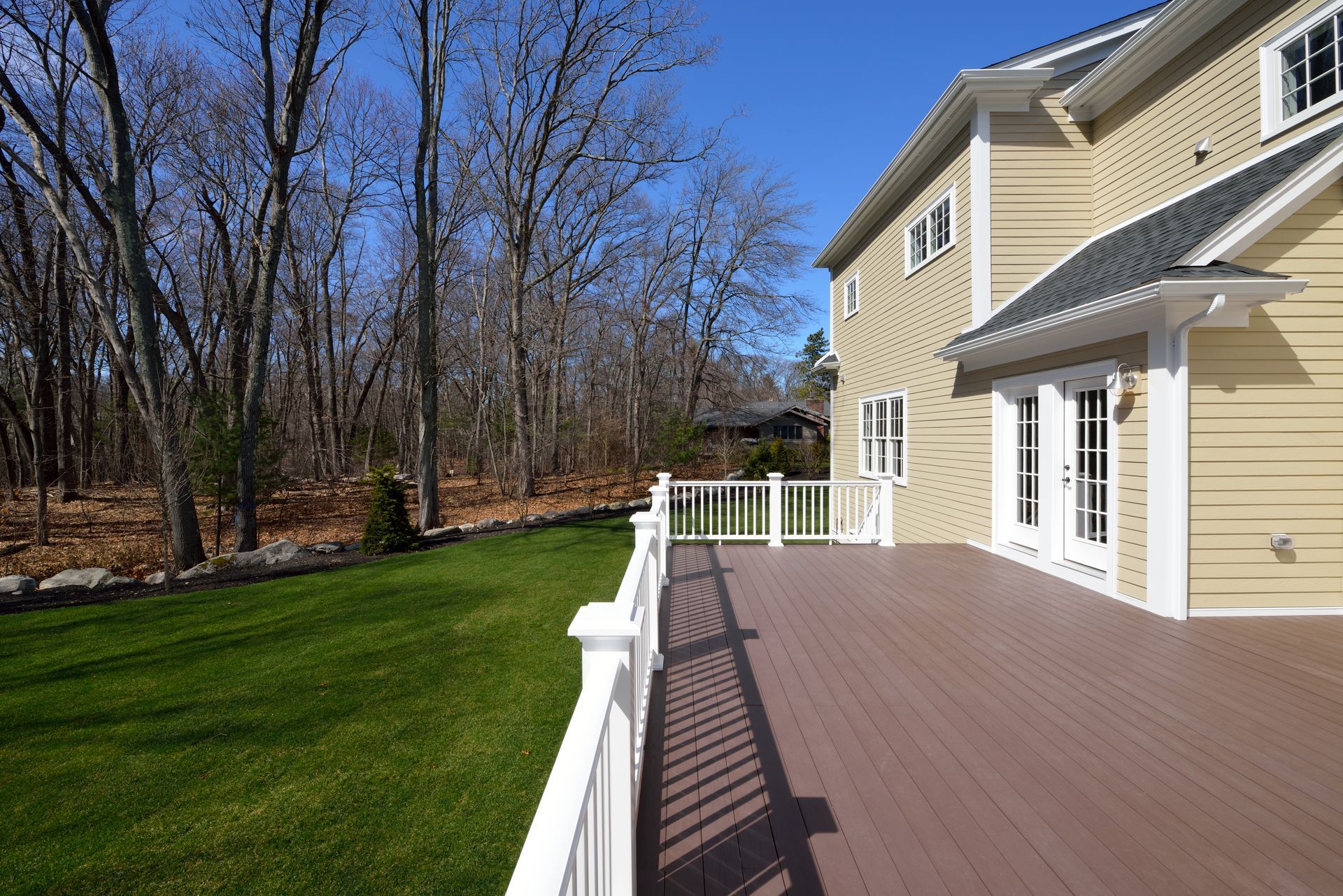 A large house with a large deck and a white fence