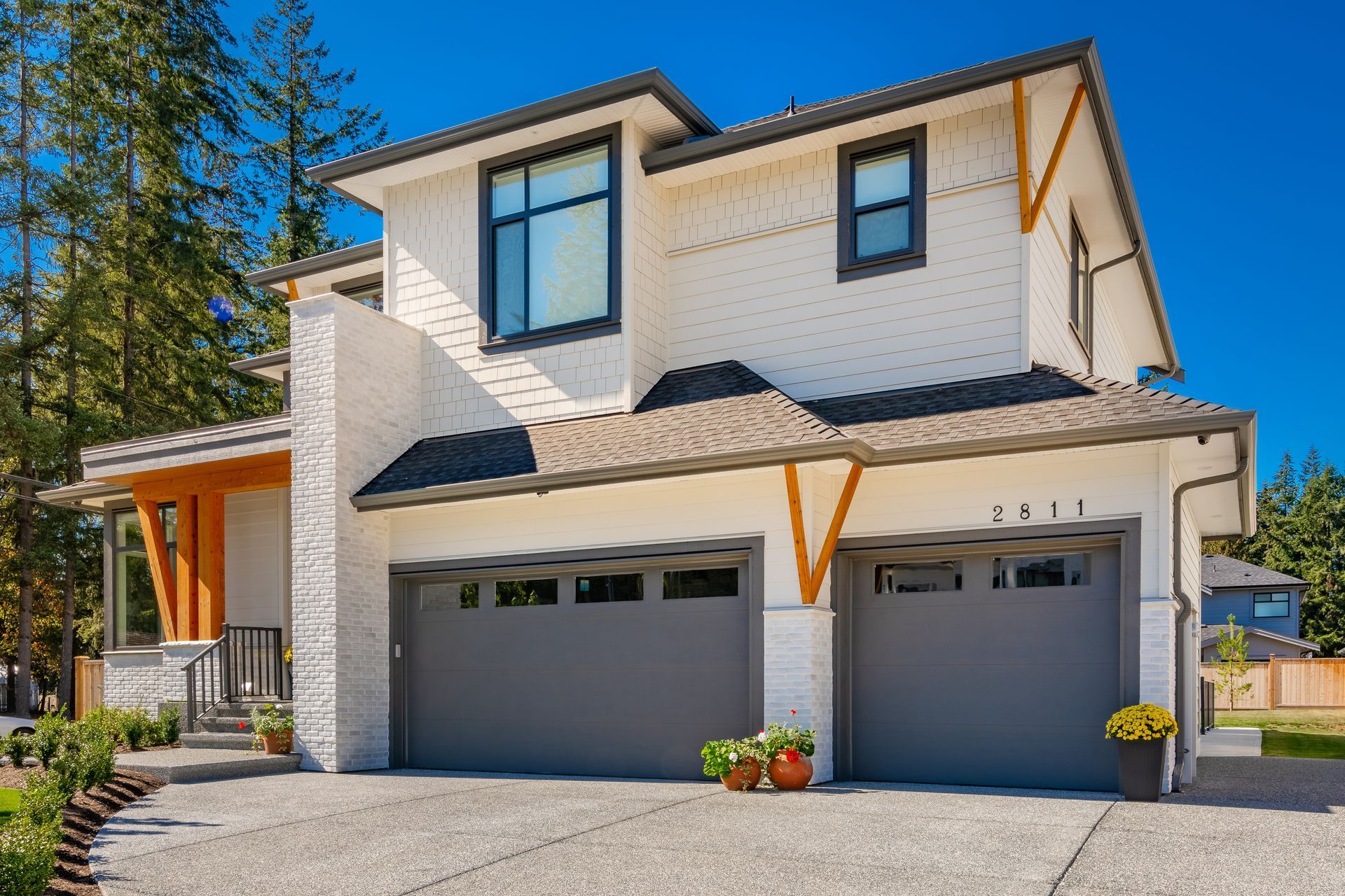 A large white house with two garage doors and a driveway.