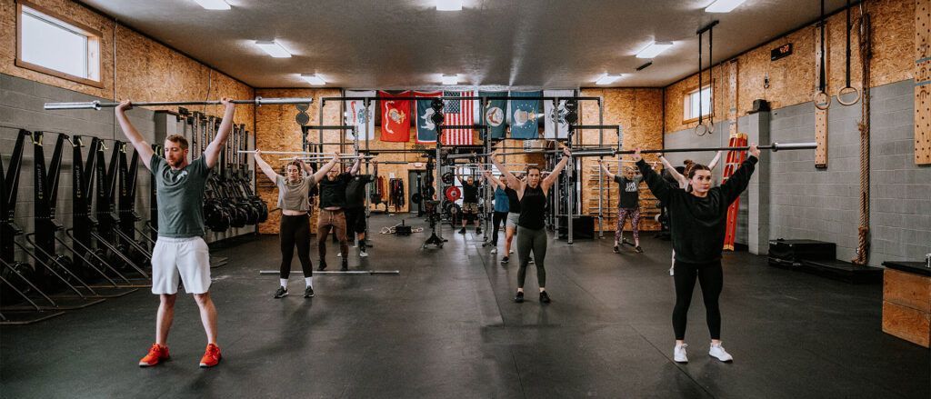 People exercising in a gym studio, arms raised in a group fitness class.