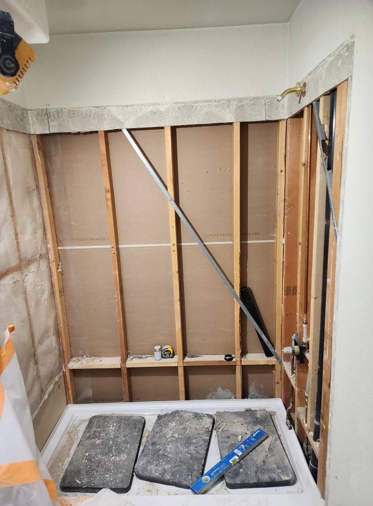 Bathroom renovation in progress, framing, plumbing visible, with a metal support brace.
