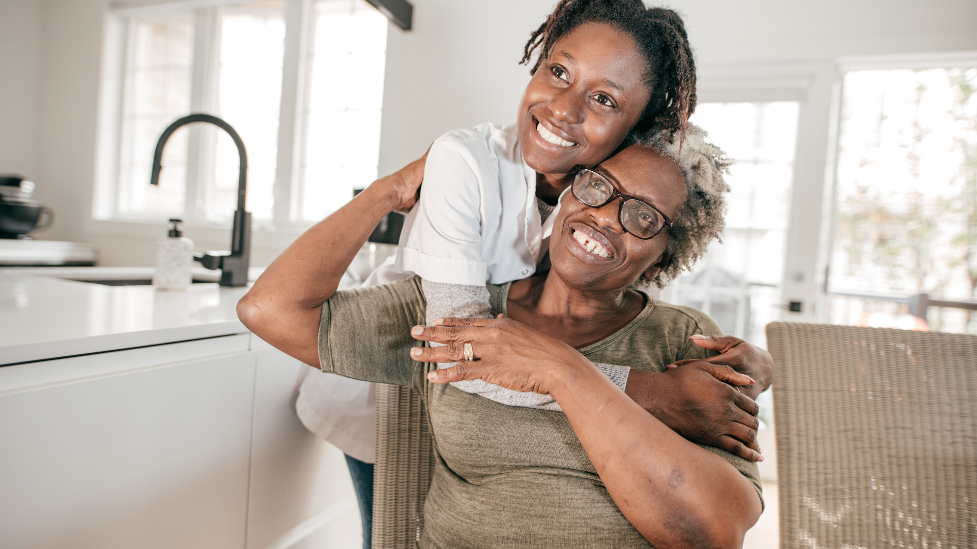 A woman is holding the hand of an older woman.