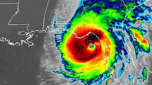 Satellite image of a hurricane over Florida; red and yellow eye, spiraling clouds in green and blue.