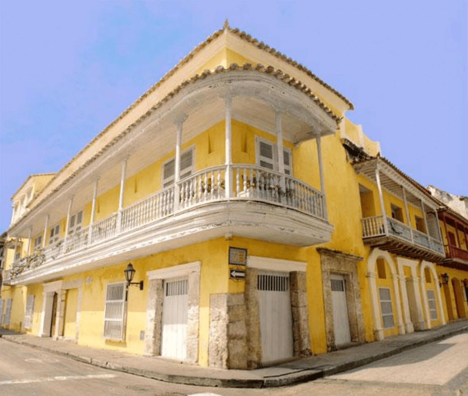 Un edificio amarillo con balcón está en la esquina de una calle.