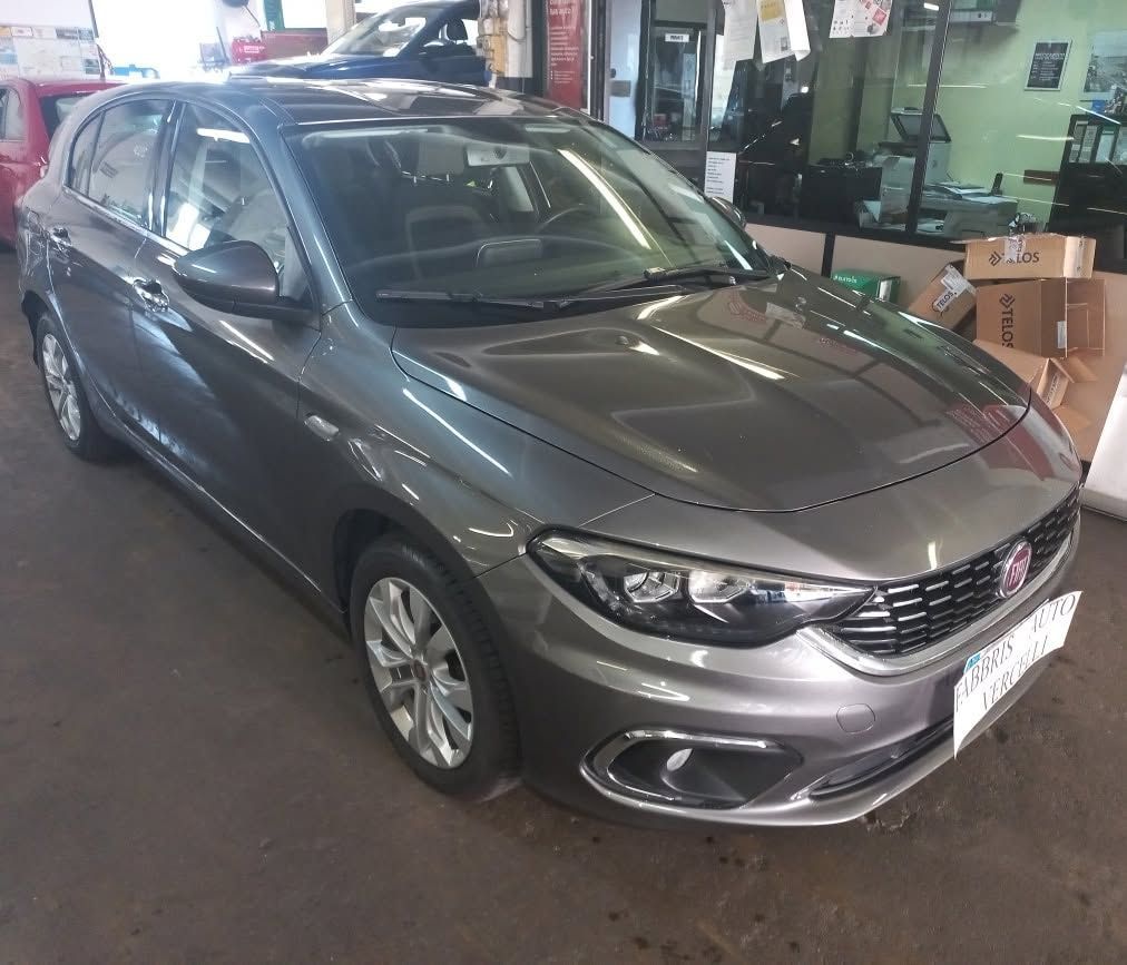 Auto hatchback grigia parcheggiata all'interno di un garage o di uno showroom, vista frontale sinistra.