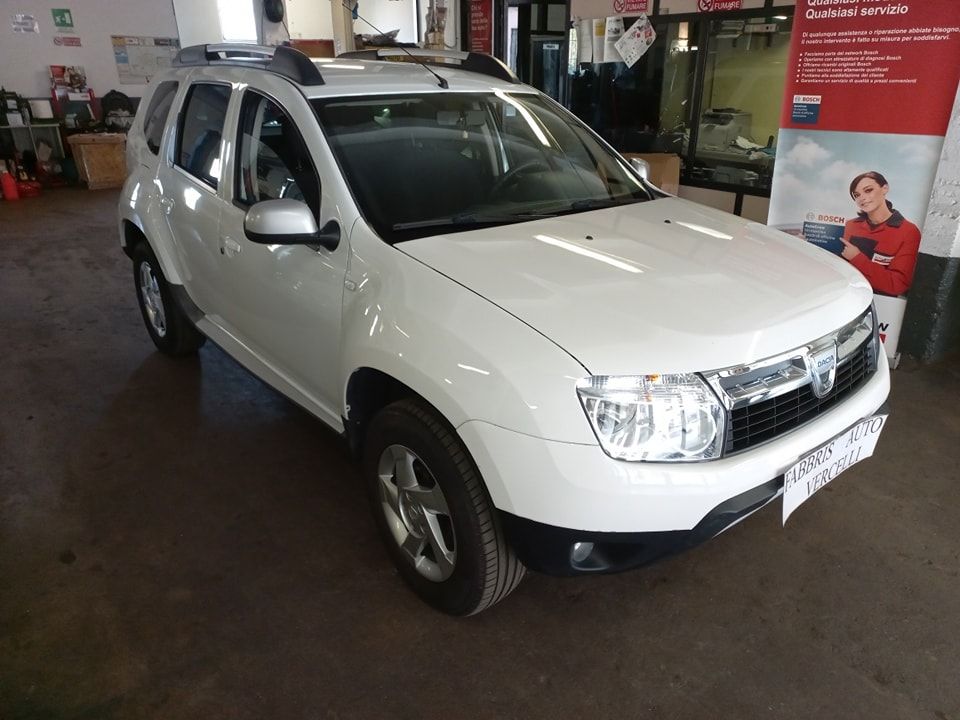 SUV bianco parcheggiato all'interno di un'officina, vista frontale sinistra.