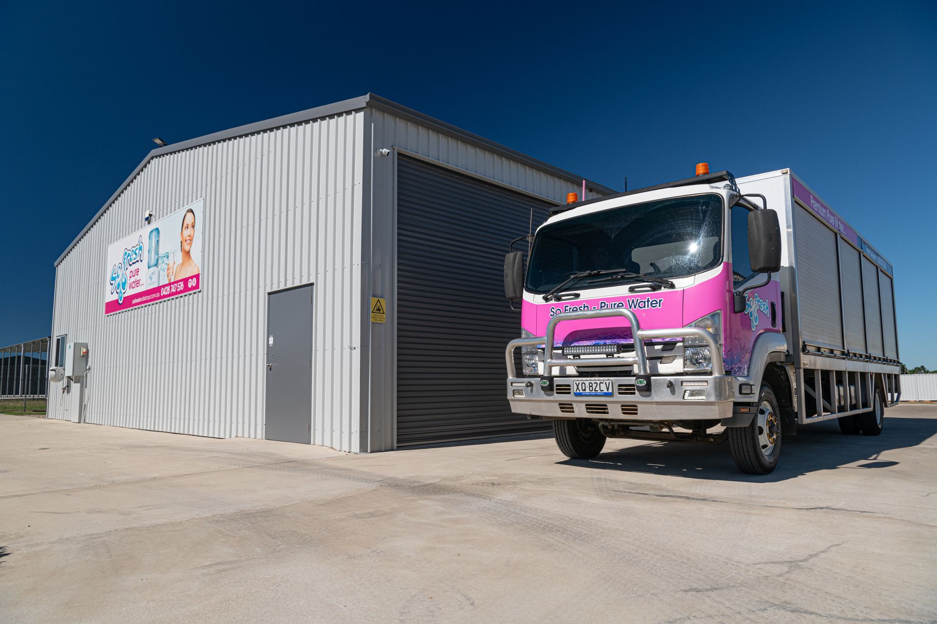 Pink truck parked beside a grey warehouse under a clear sky — So Fresh Wide Bay in Innes Park, QLD