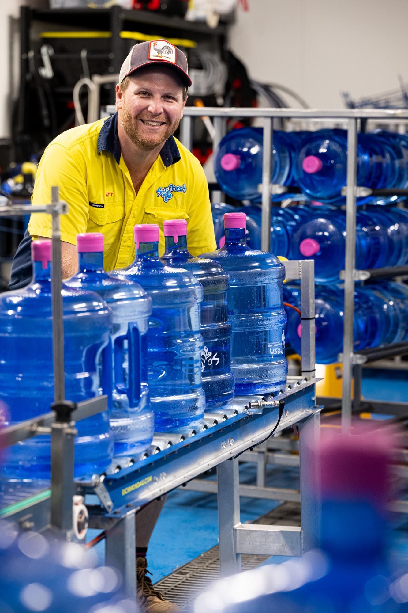Smiling Worker in Yellow Shirt Beside Conveyor — So Fresh Wide Bay in Thabeban, QLD