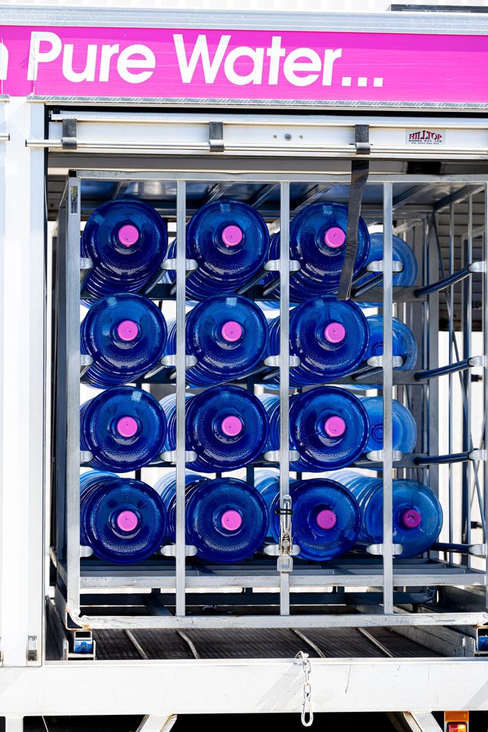 Stacked Blue Water Jugs Inside a Beverage Delivery Truck Under a Pink “pure Water” Sign — So Fresh Wide Bay in Thabeban, QLD