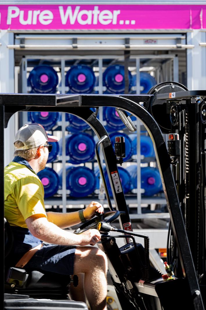 Worker Sitting on a Forklift in Front of Stacked Blue Water Jugs Labelled “pure Water” — So Fresh Wide Bay in Thabeban, QLD