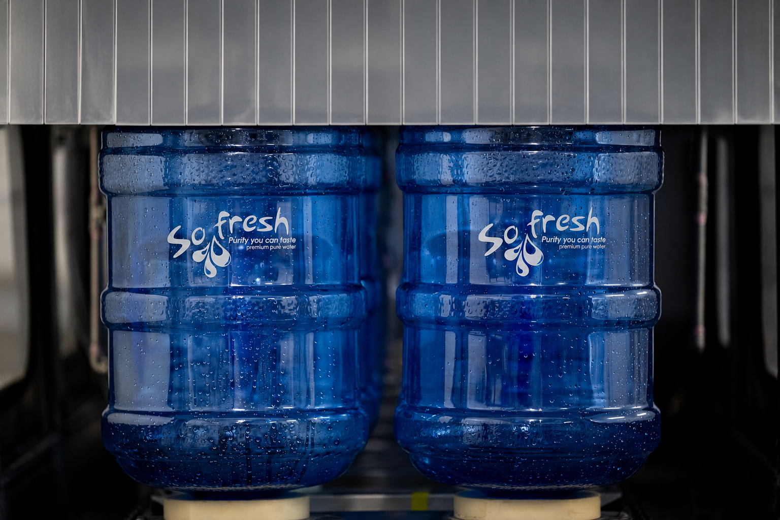 Two blue water jugs on a dispenser shelf with “So fresh” labels