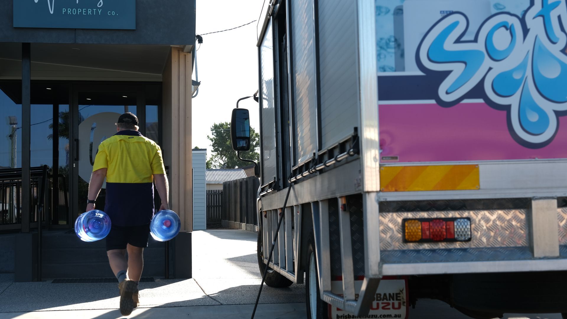 Person in yellow shirt carrying blue buckets walks between trucks at a loading dock