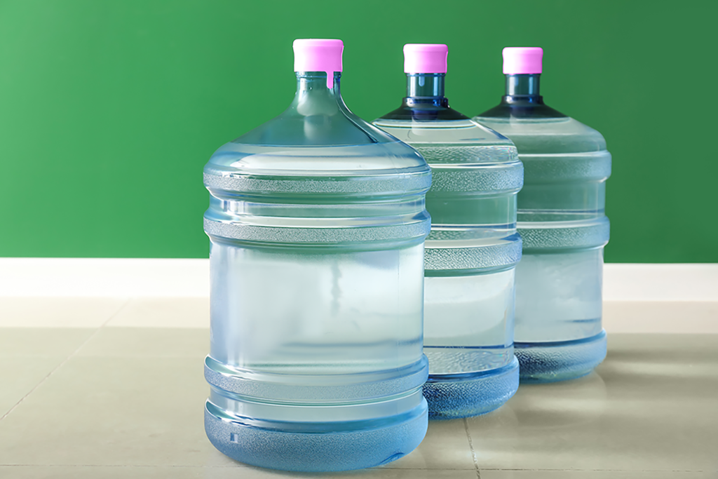 Three Large Water Jugs With Pink Caps on a Tabletop Against a Green Wall — So Fresh Wide Bay in Thabeban, QLD