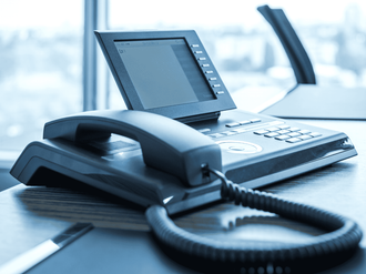 A telephone is sitting on a desk in front of a window
