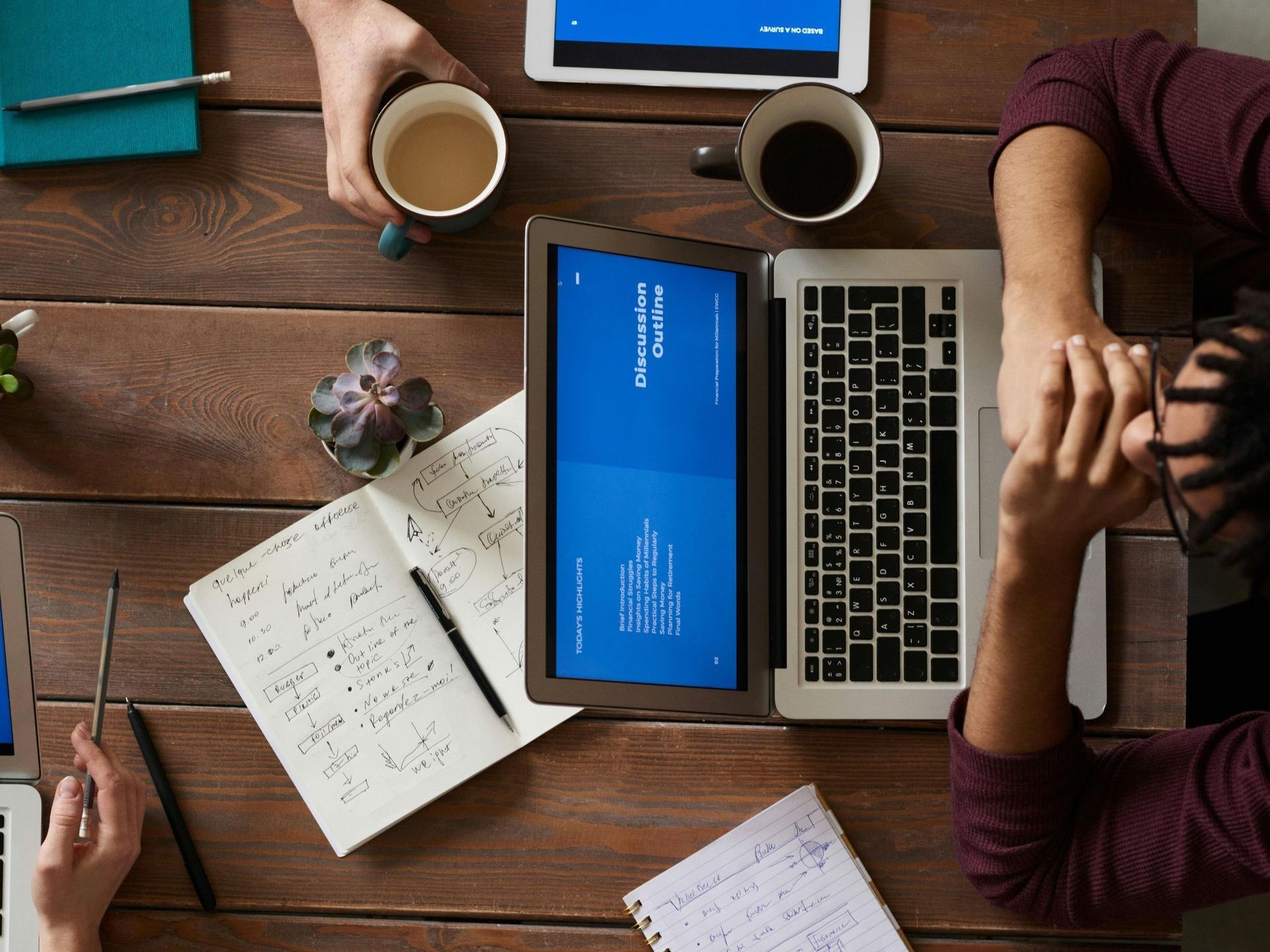 A man is sitting at a table with a laptop and a cup of coffee.