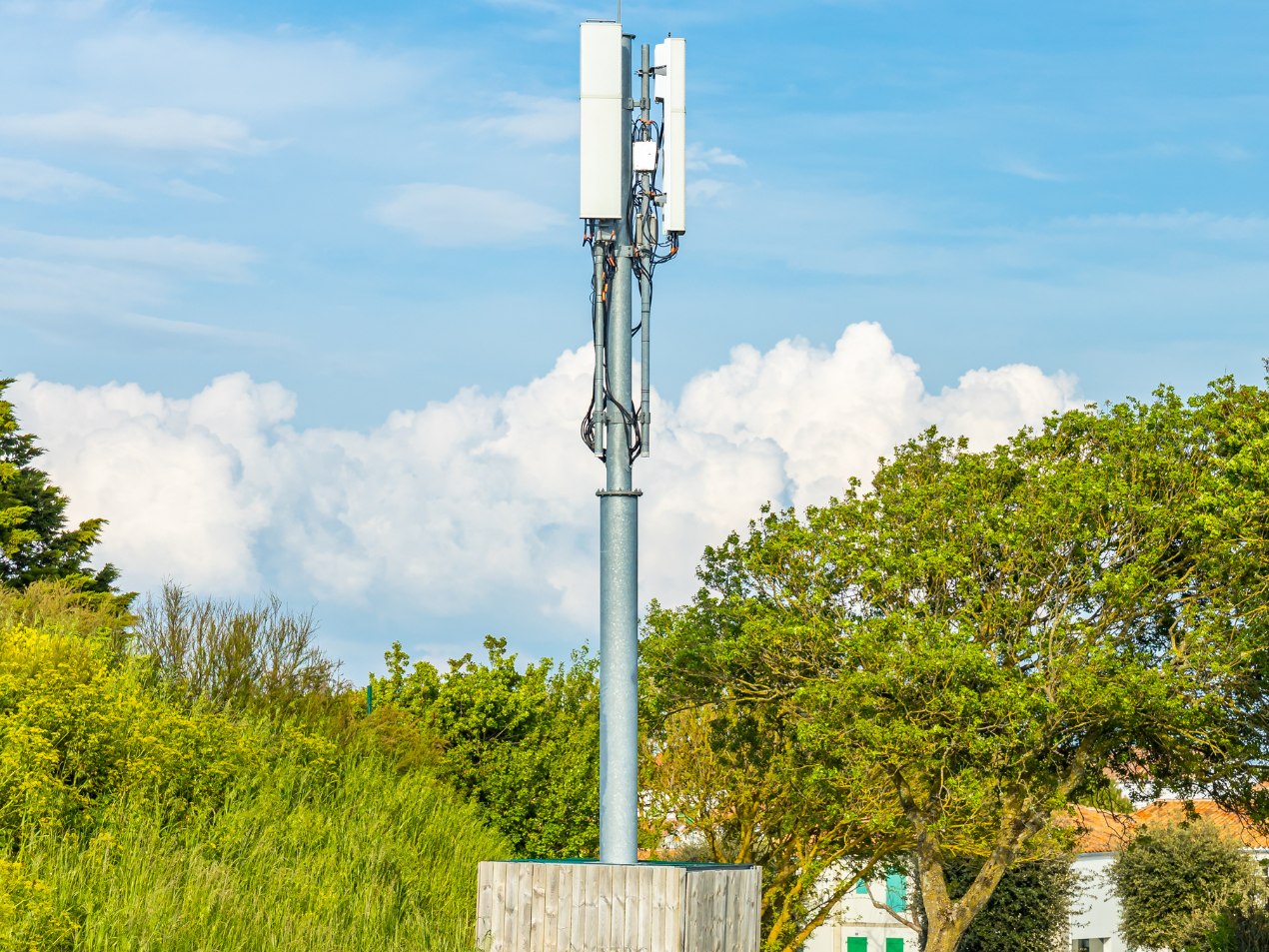 A cell phone tower is sitting in the middle of a field surrounded by trees.
