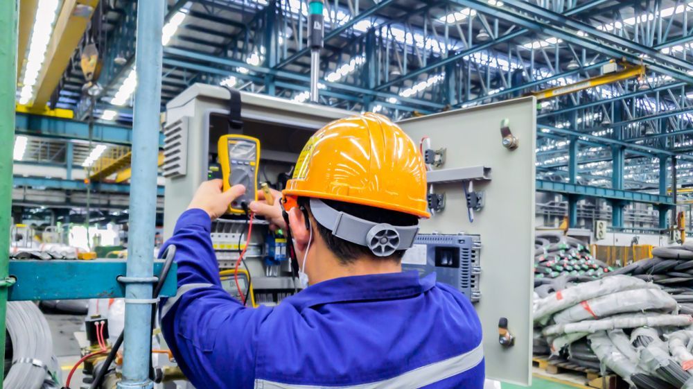 A Man in a Hard Hat is Working on a Machine in a Factory — Advantage Communications & Electrical in Maroochydore, QLD