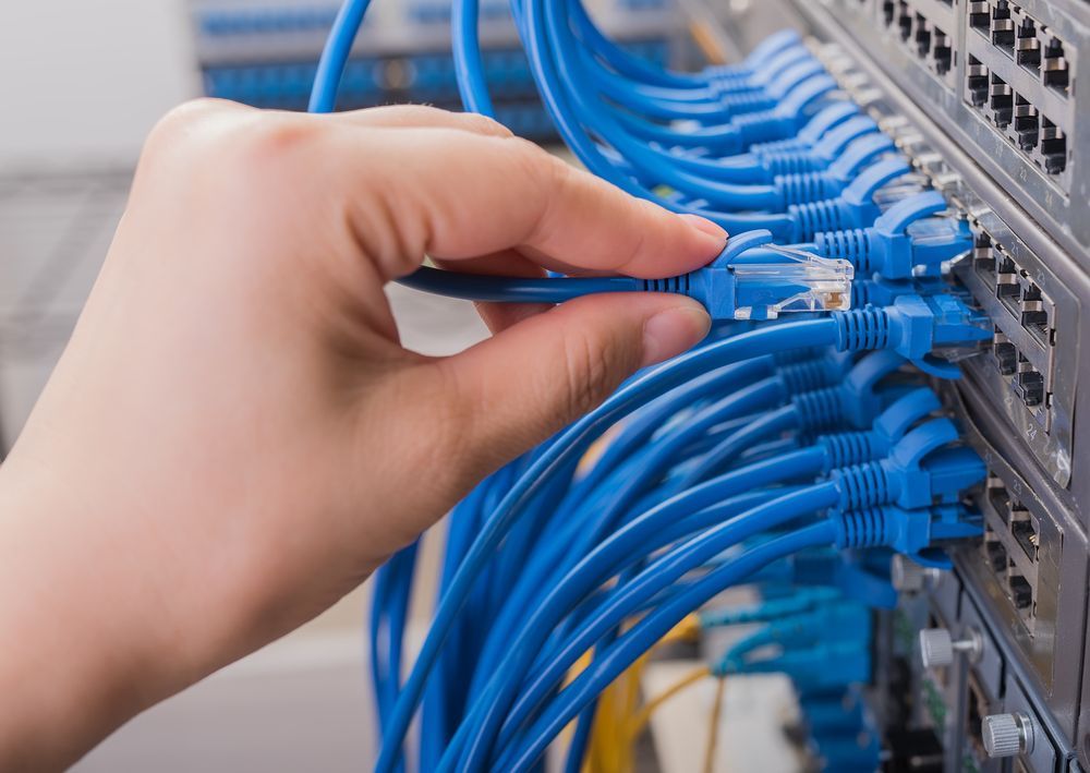 A Person is Plugging a Blue Cable Into a Server — Advantage Communications & Electrical in Maroochydore, QLD