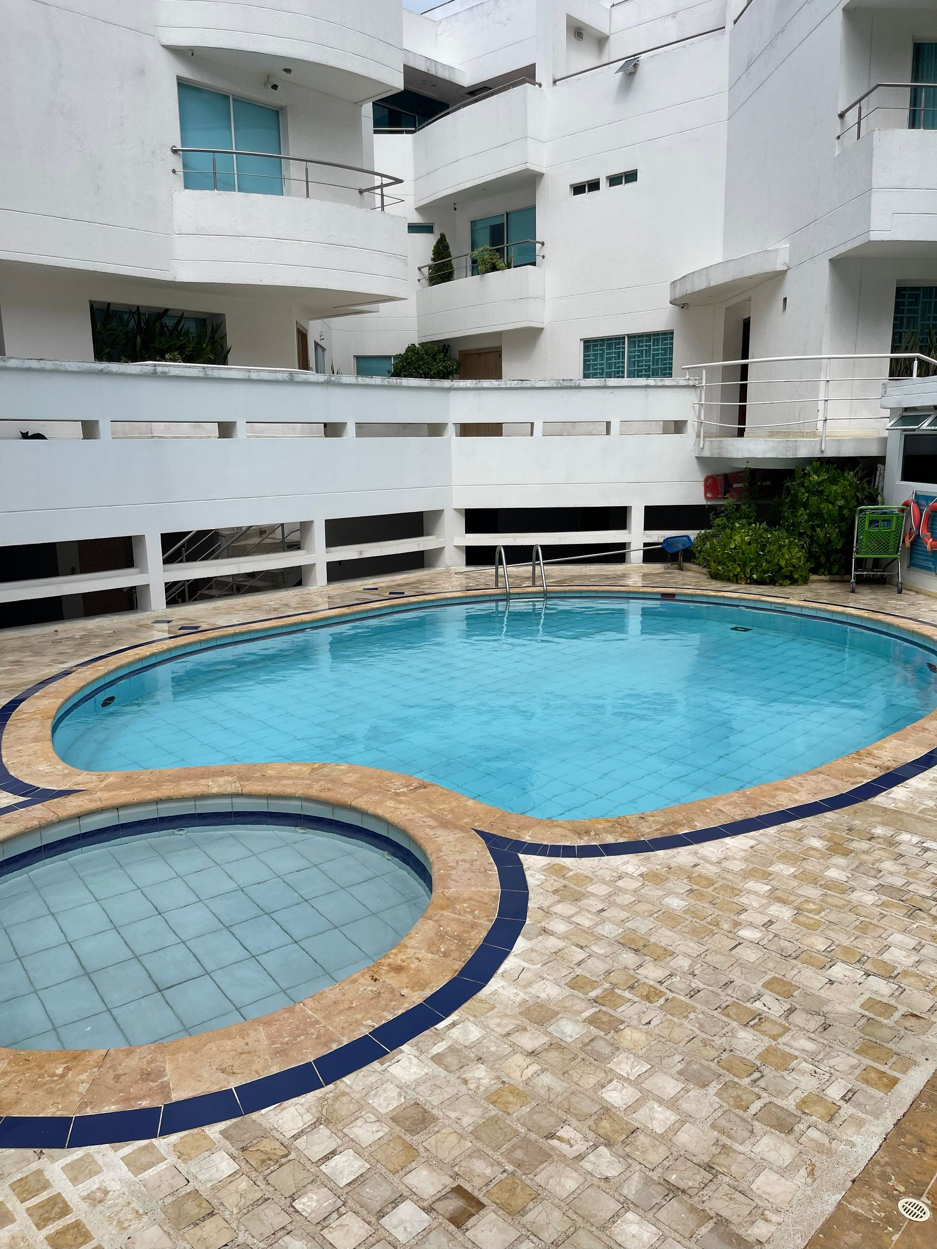 Piscina y jacuzzi en un patio con edificios blancos.