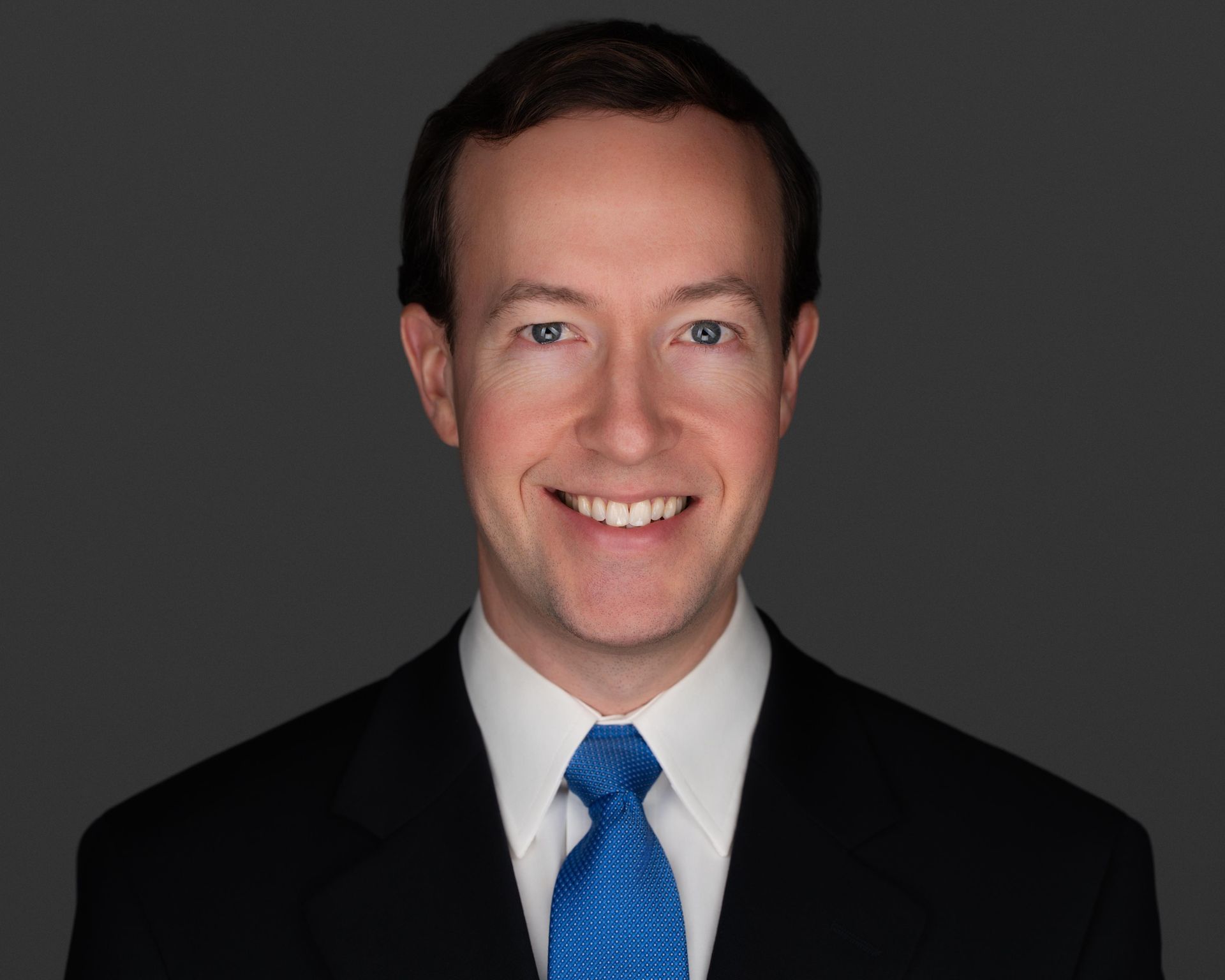 A man in a suit and tie is smiling for the camera.
