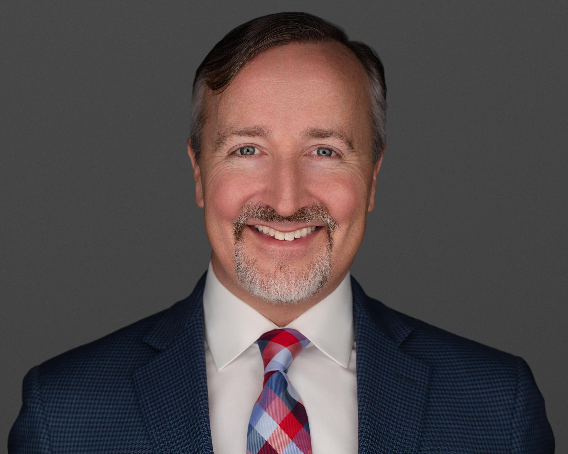 A man in a suit and tie is smiling for the camera.