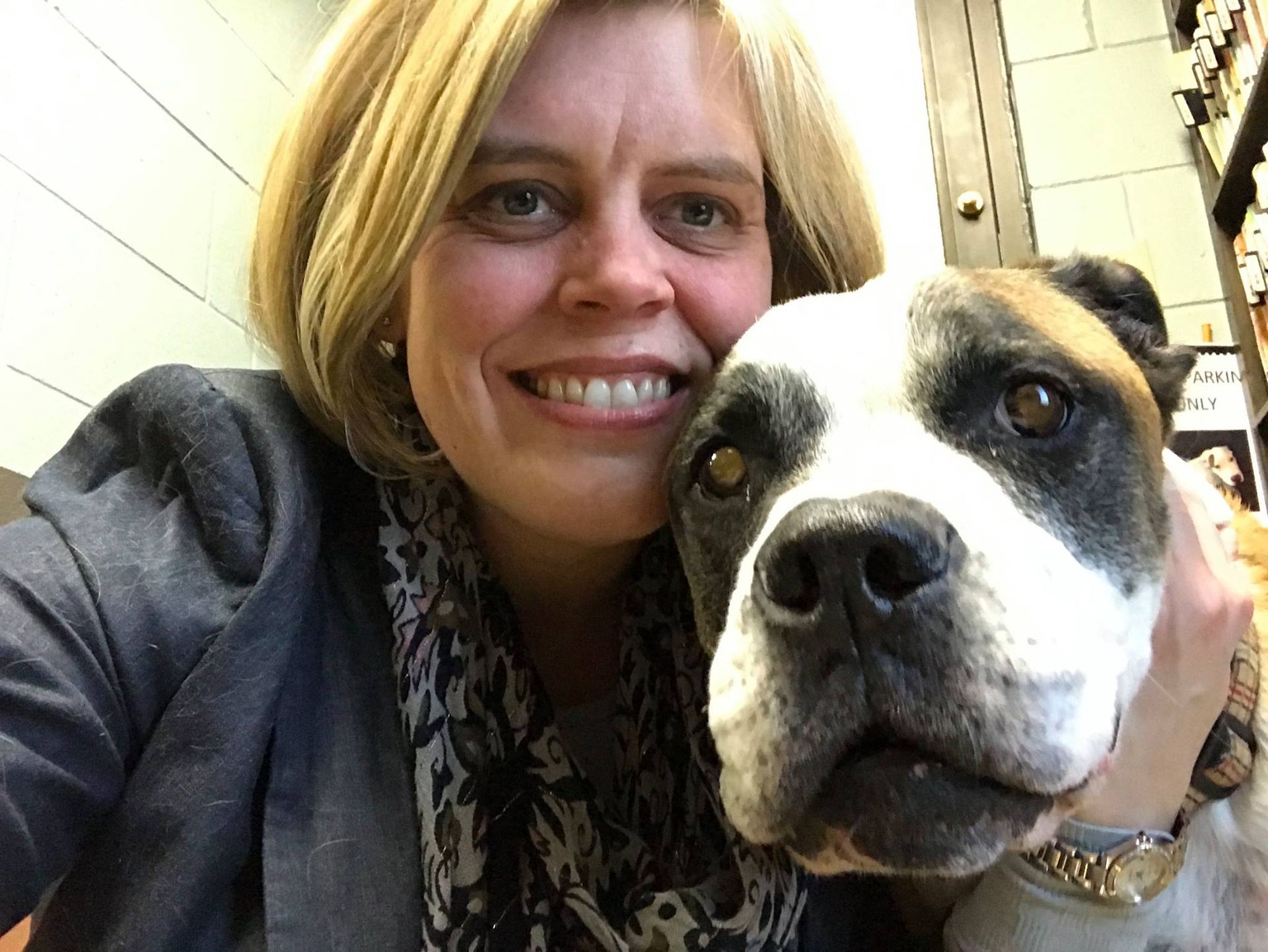 Woman smiling beside a large black-and-white dog in a close-up indoor selfie