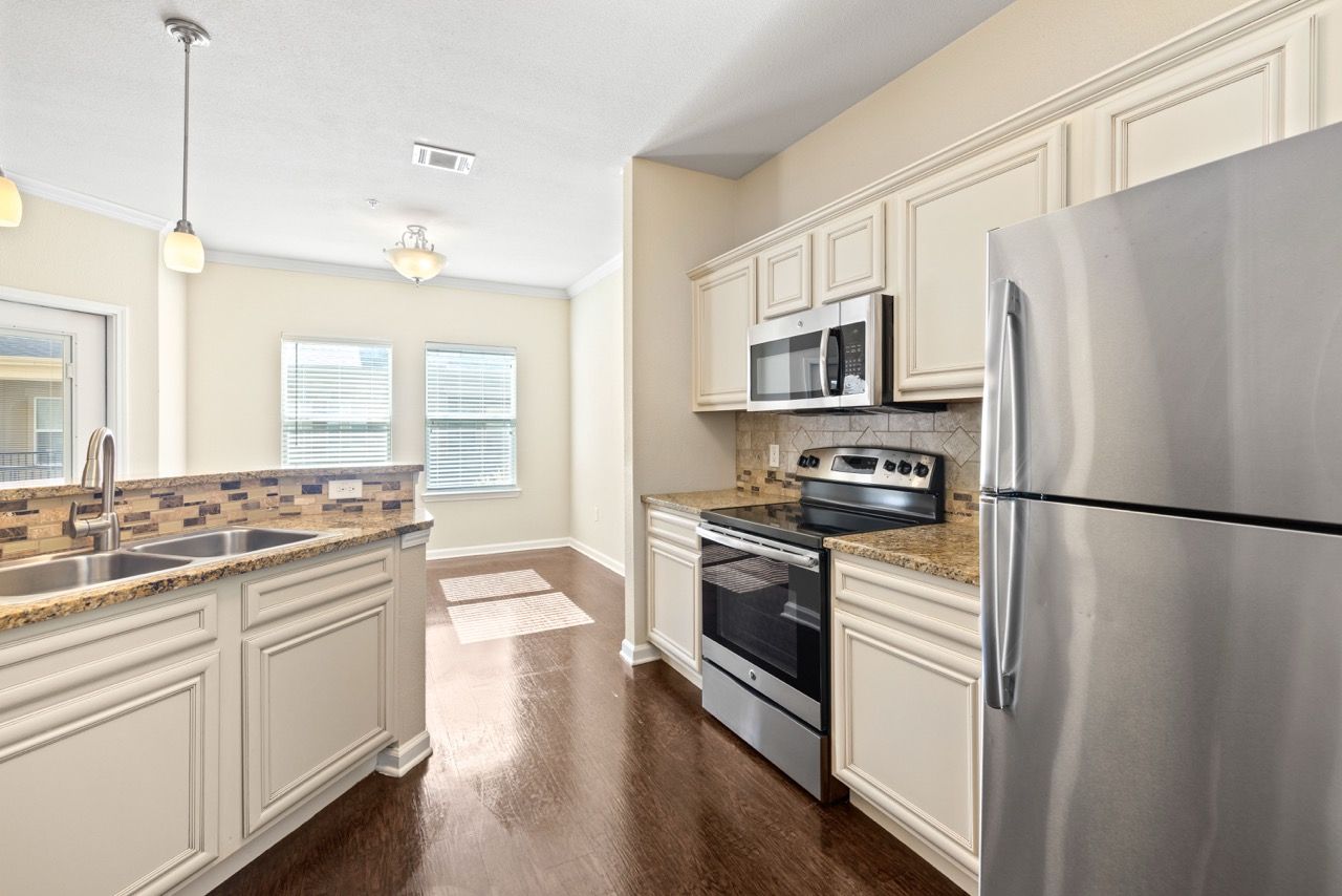 Open-concept kitchen with stainless steel appliances, granite countertops, and white cabinets.