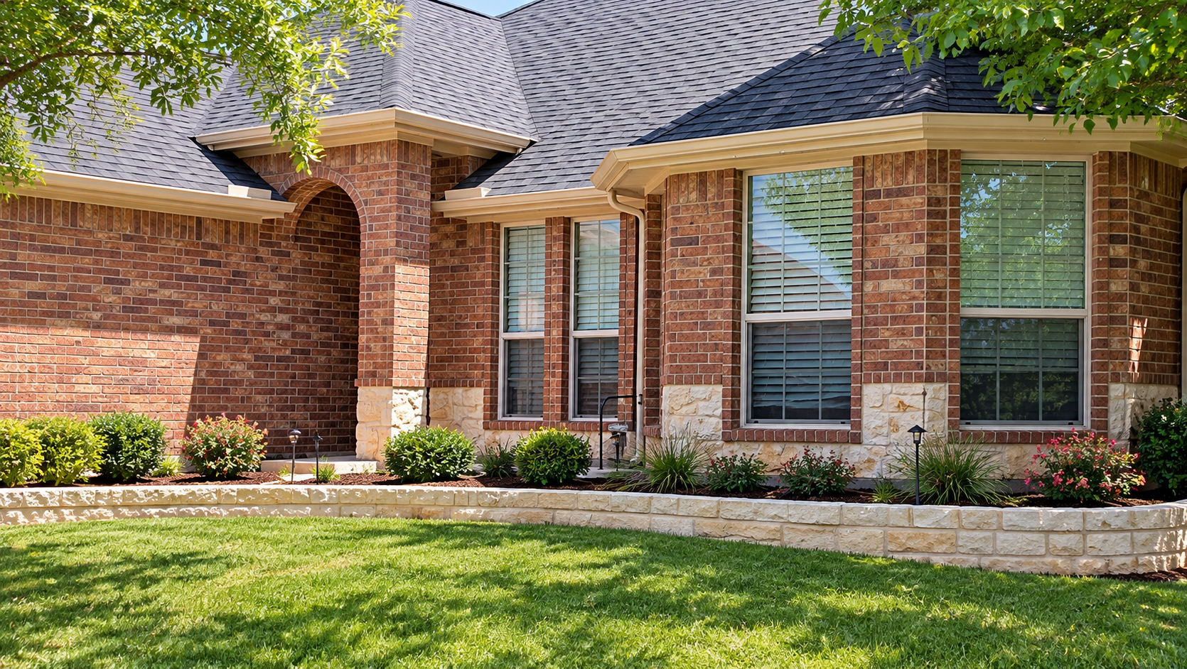 Brick suburban house with arched windows, gray roof, and green front lawn