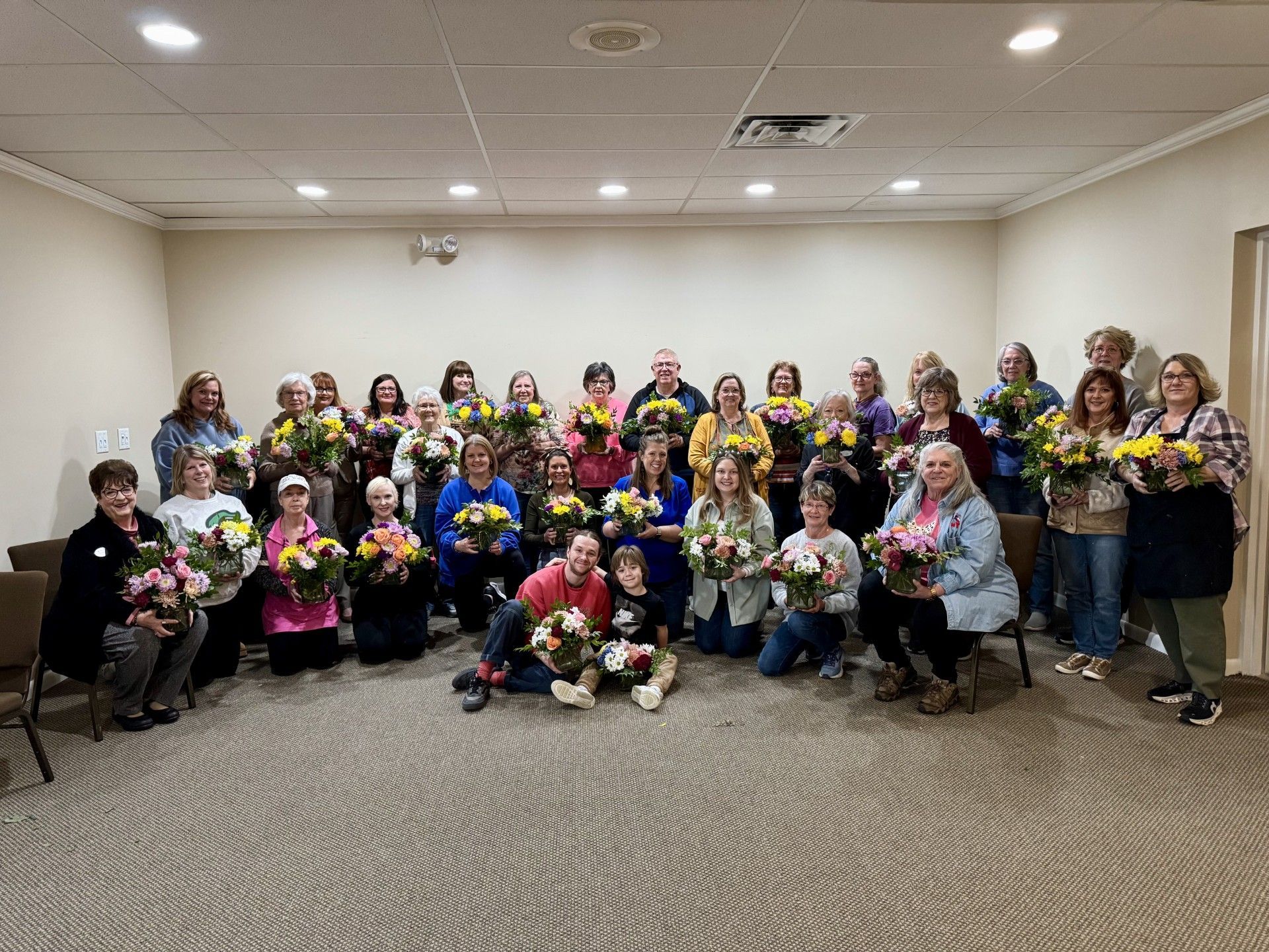 A group of people are posing for a picture in a room holding bouquets of flowers.
