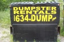 Black dumpster with yellow “Dumpster Rentals” and “634-DUMP” lettering on the front