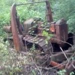 Rusty old machine wreck in tall grass and weeds outdoors