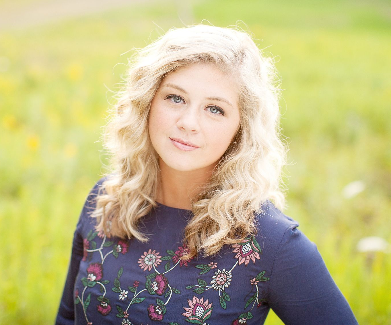 Close-up portrait of a high school senior with natural lighting and a soft outdoor background.