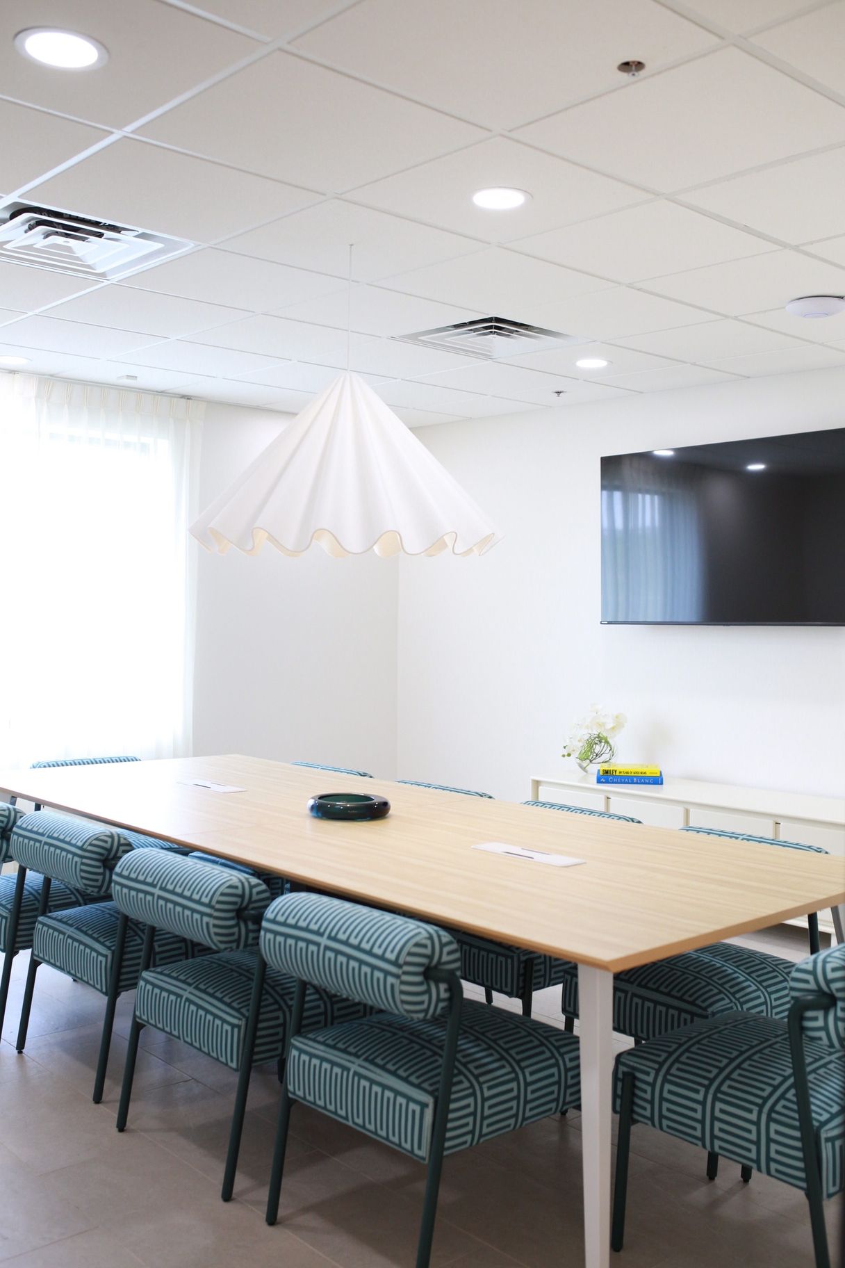 A conference room with a long table and chairs and a flat screen tv.