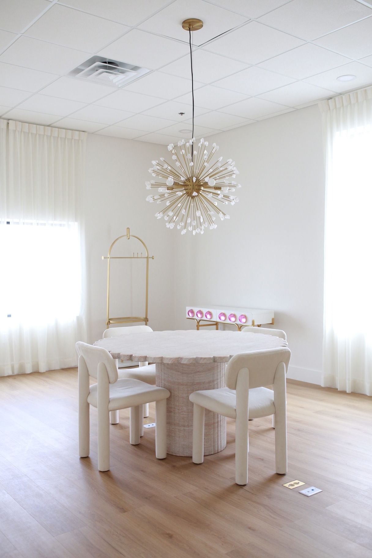 A dining room with a table and chairs and a chandelier hanging from the ceiling.