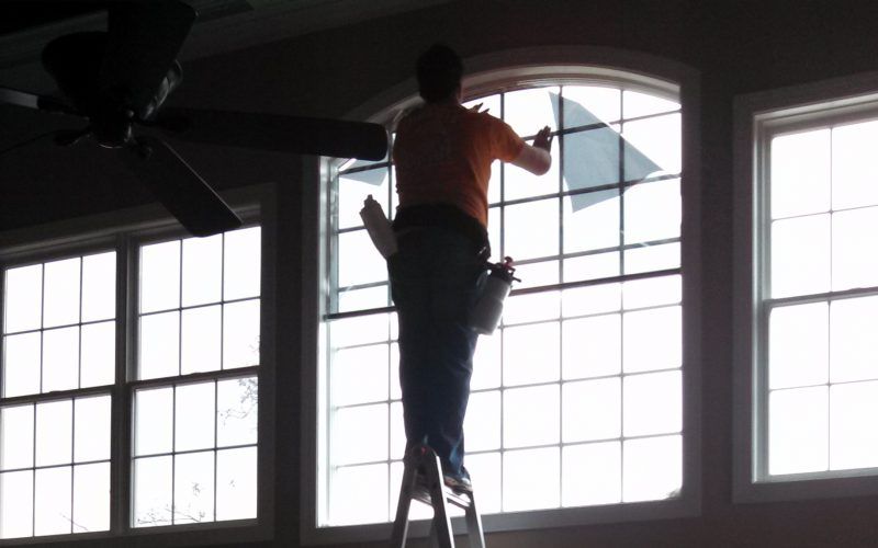 A man is standing on a ladder cleaning a window