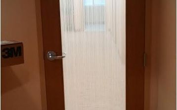 A door with a striped glass covering is open to a room.