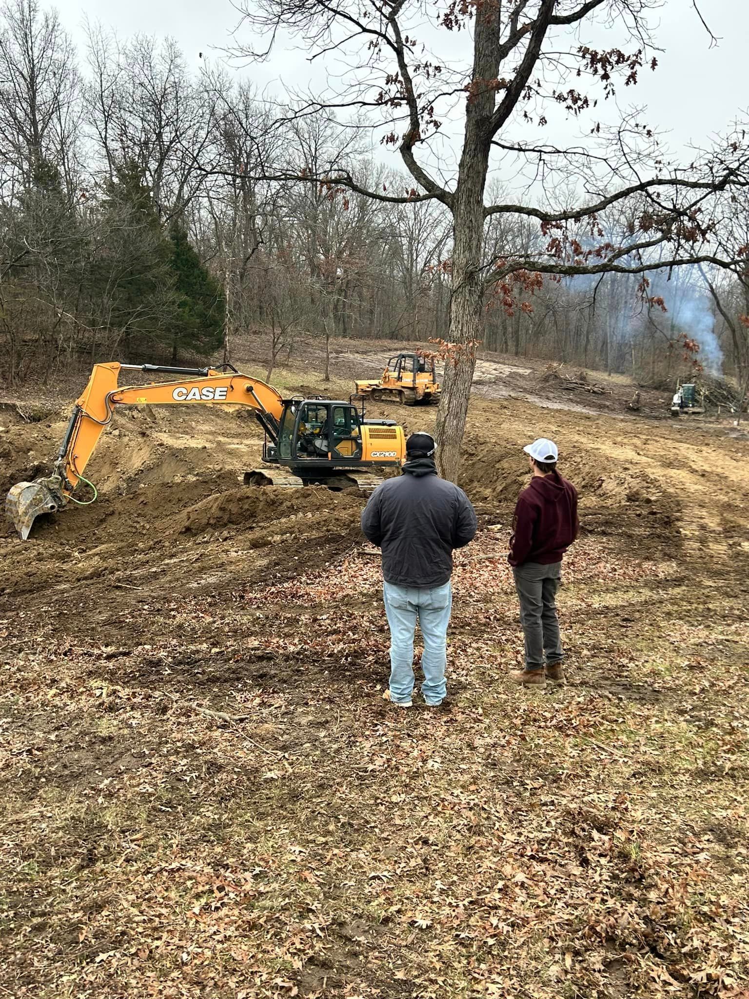 Two men are standing in a field with a bulldozer.