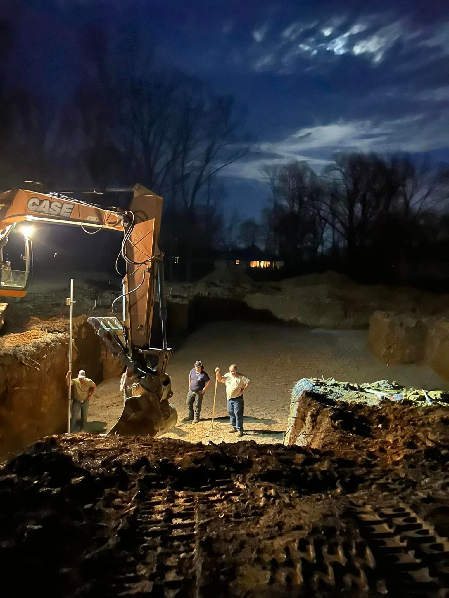 A group of construction workers are working on a construction site at night.