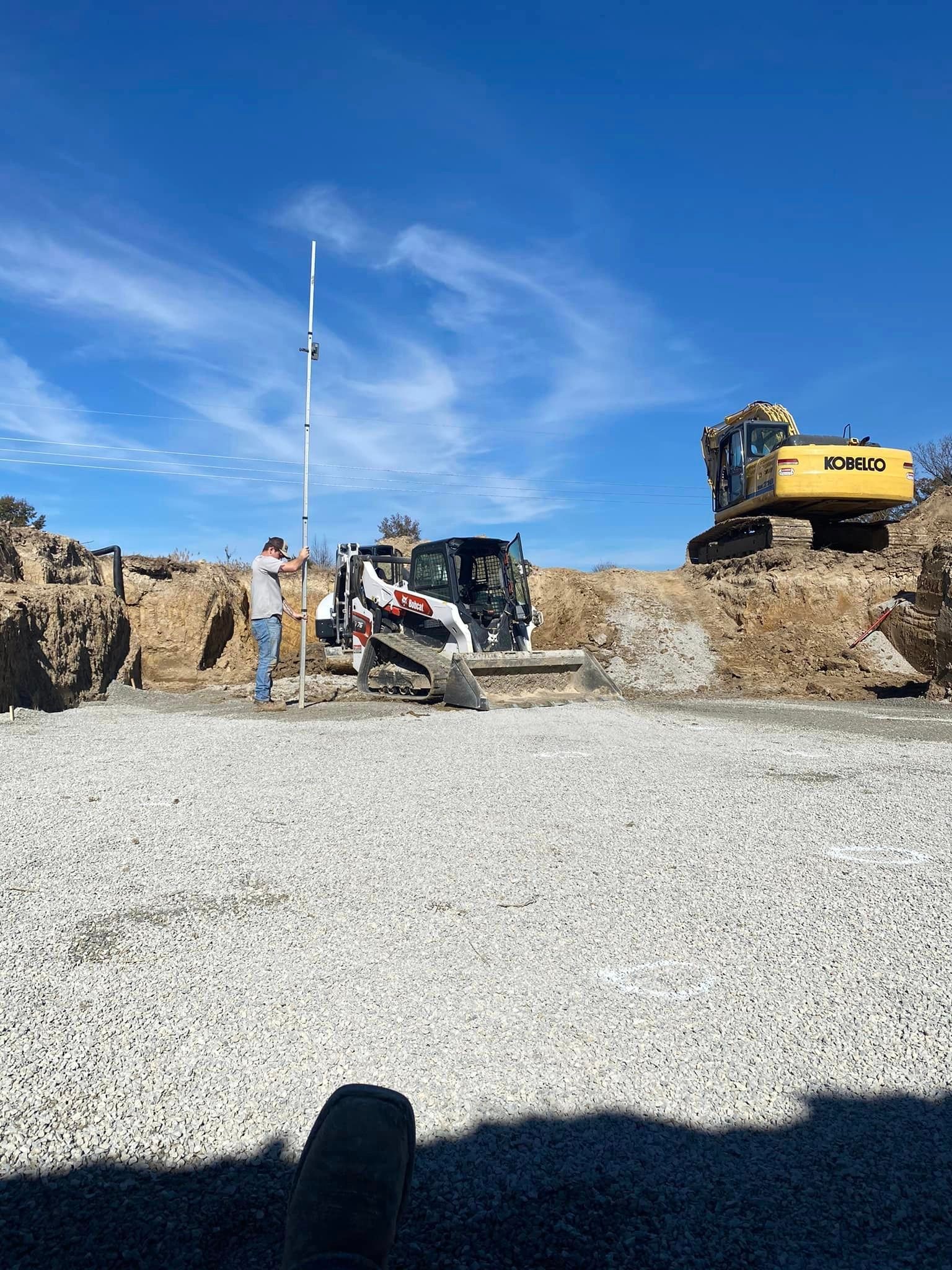 A man is standing next to a bulldozer on a gravel road.