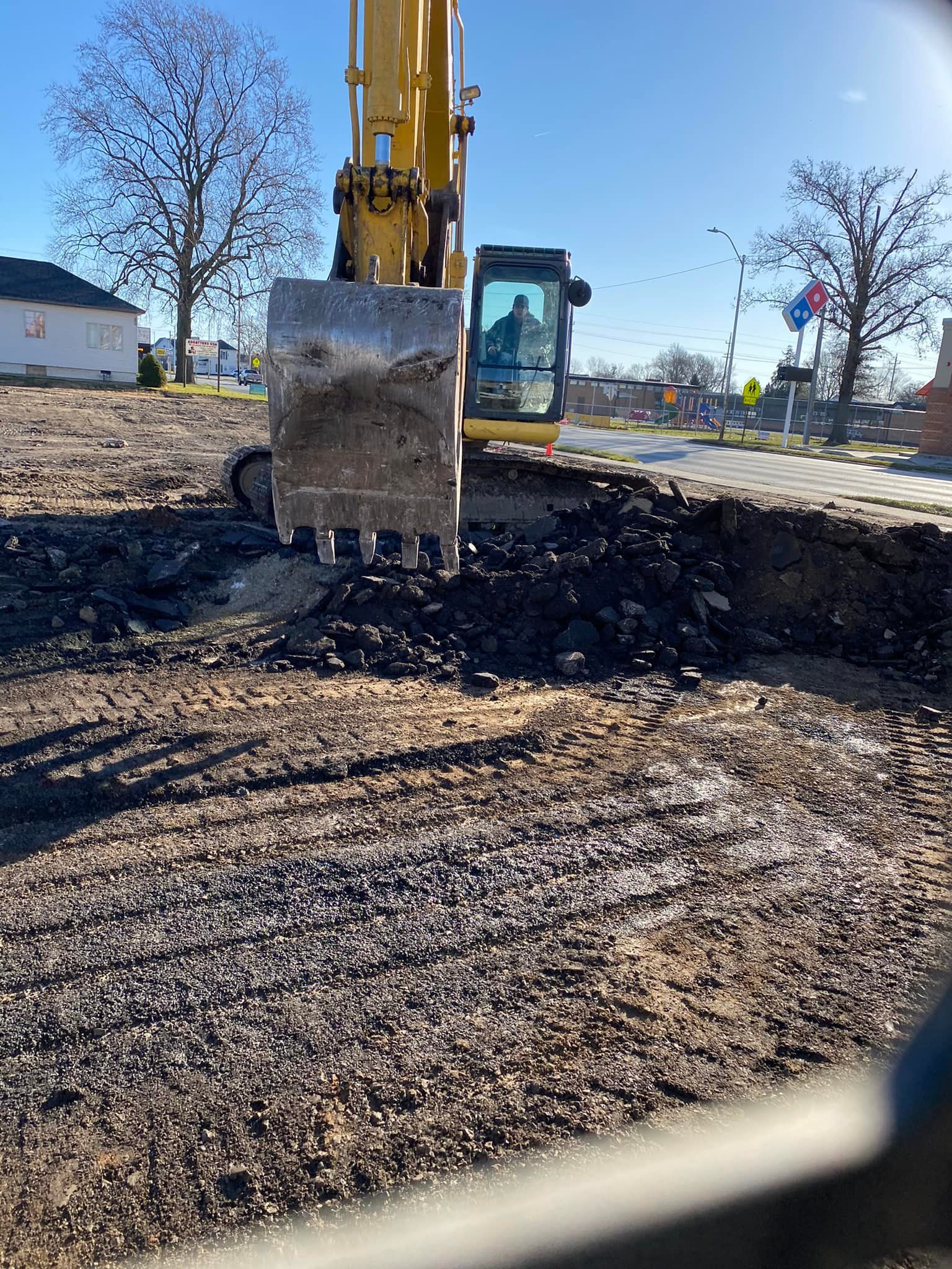 A yellow excavator is digging a hole in the ground.