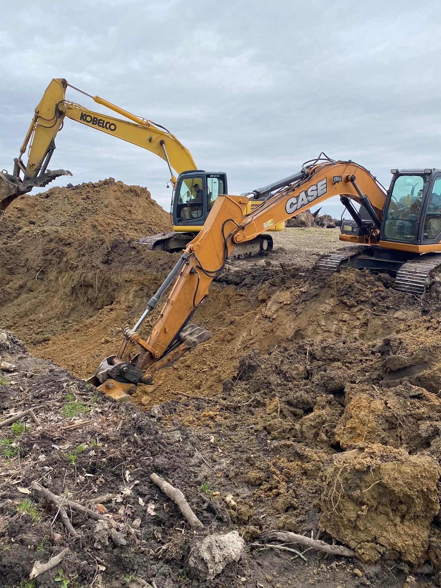 Two excavators are digging in a pile of dirt on a construction site.