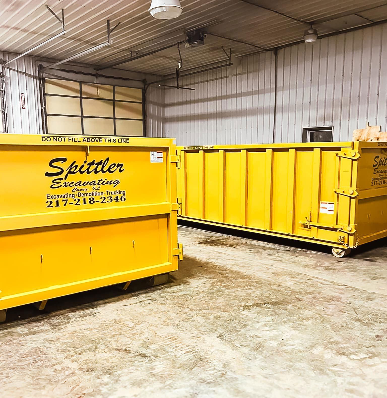 Two yellow dumpsters are sitting in a garage.