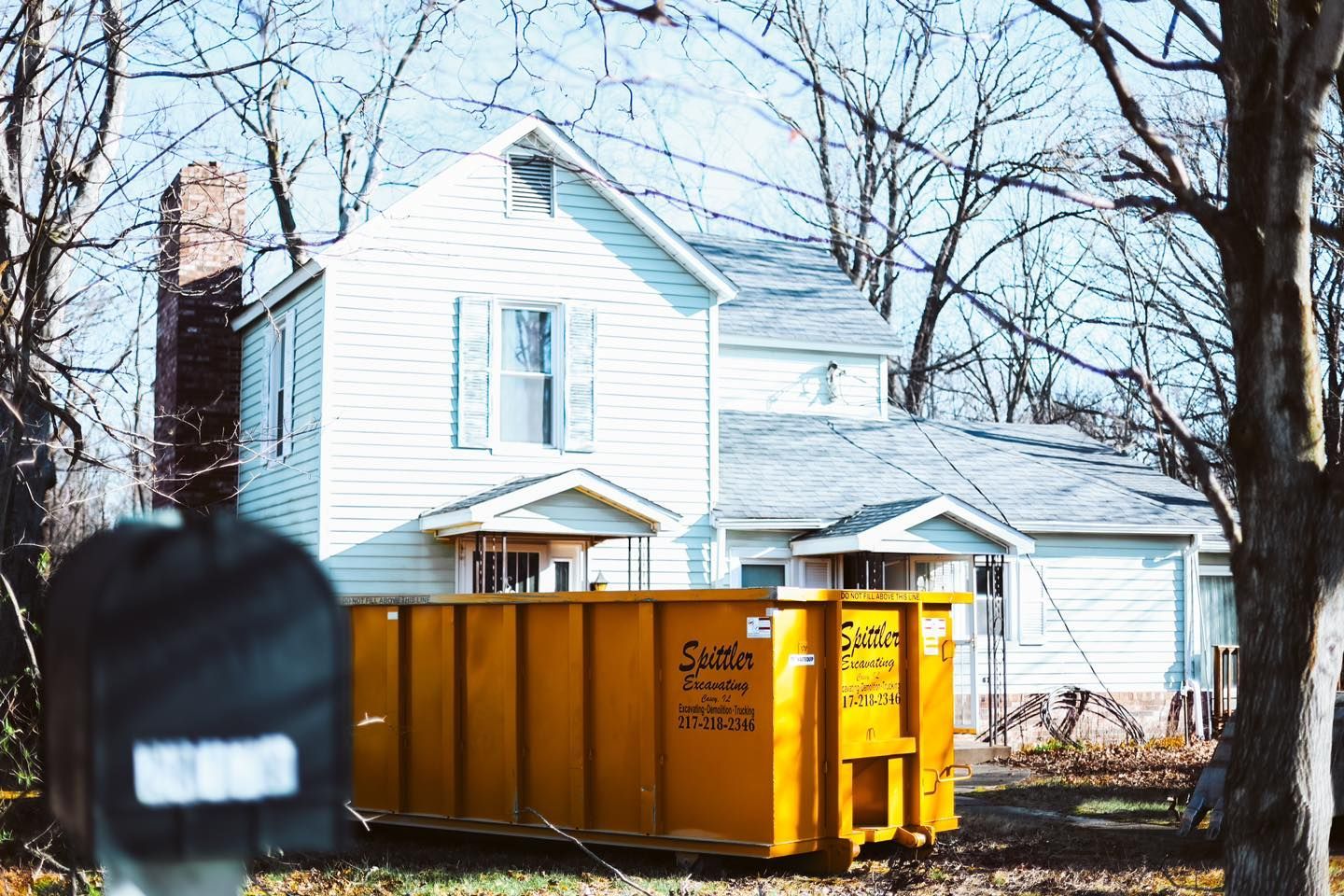 A yellow dumpster in front of a house.