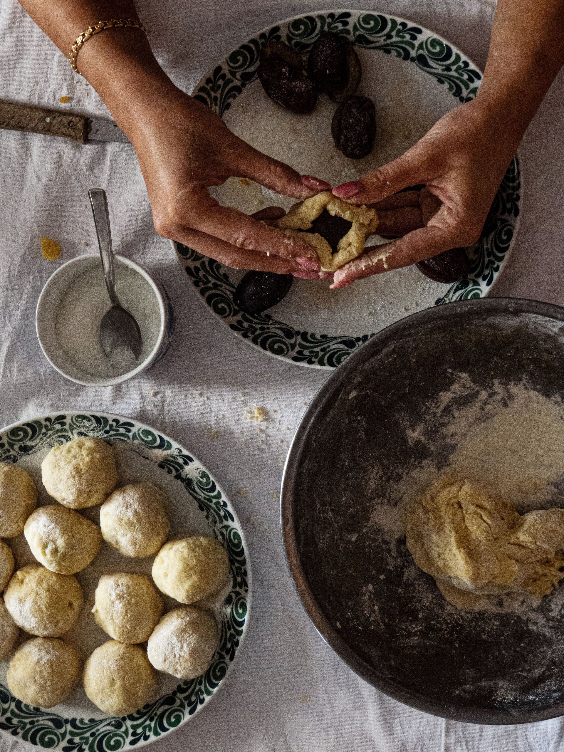 Hands shaping knedle, Central European potato dough dumplings with plums