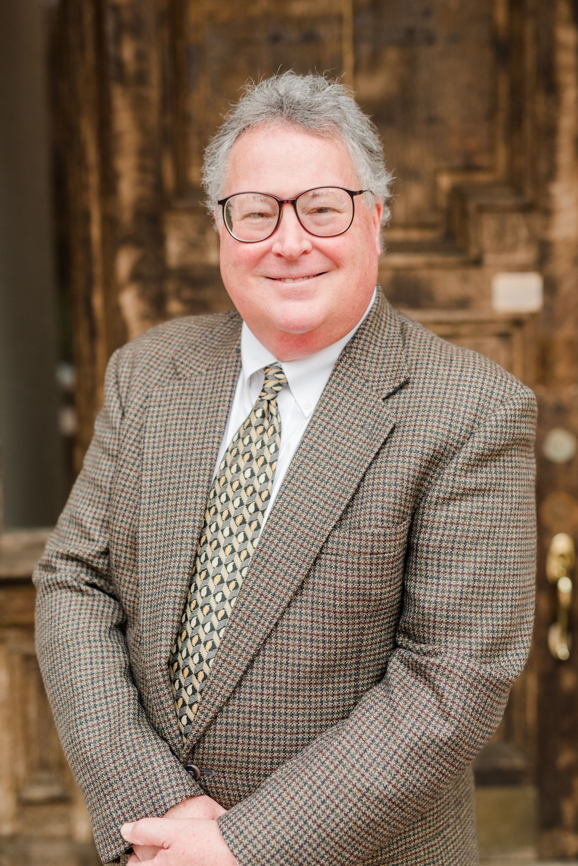 A man in a suit and tie is standing in front of a door.