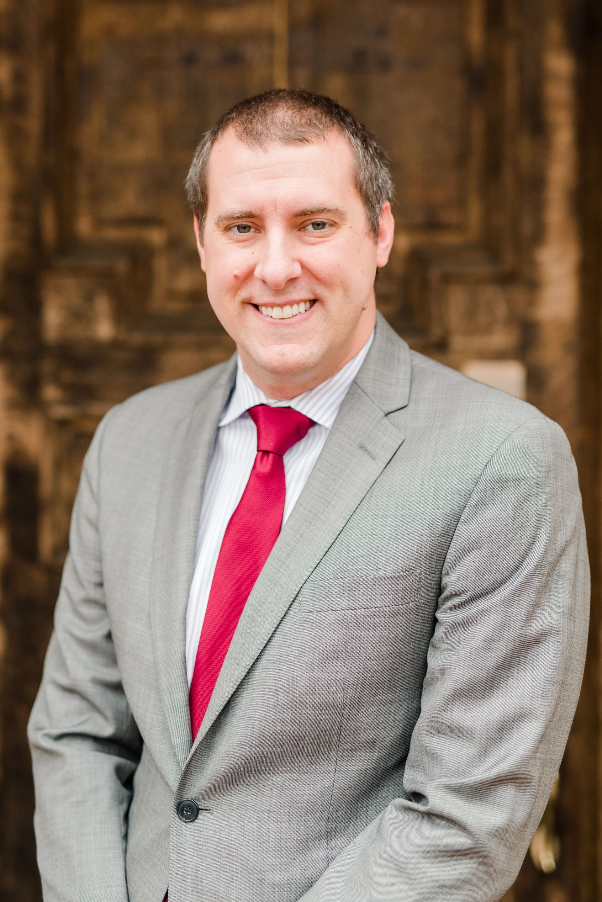 A man in a suit and red tie is smiling for the camera.