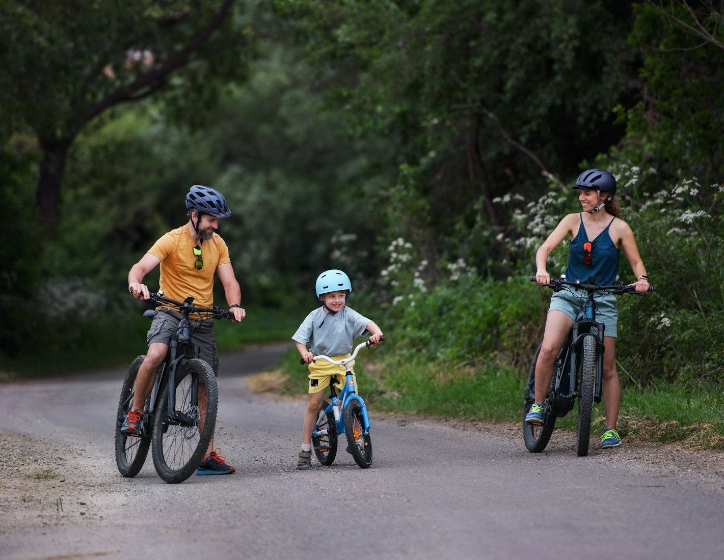 A man , woman and child are riding bicycles down a road.