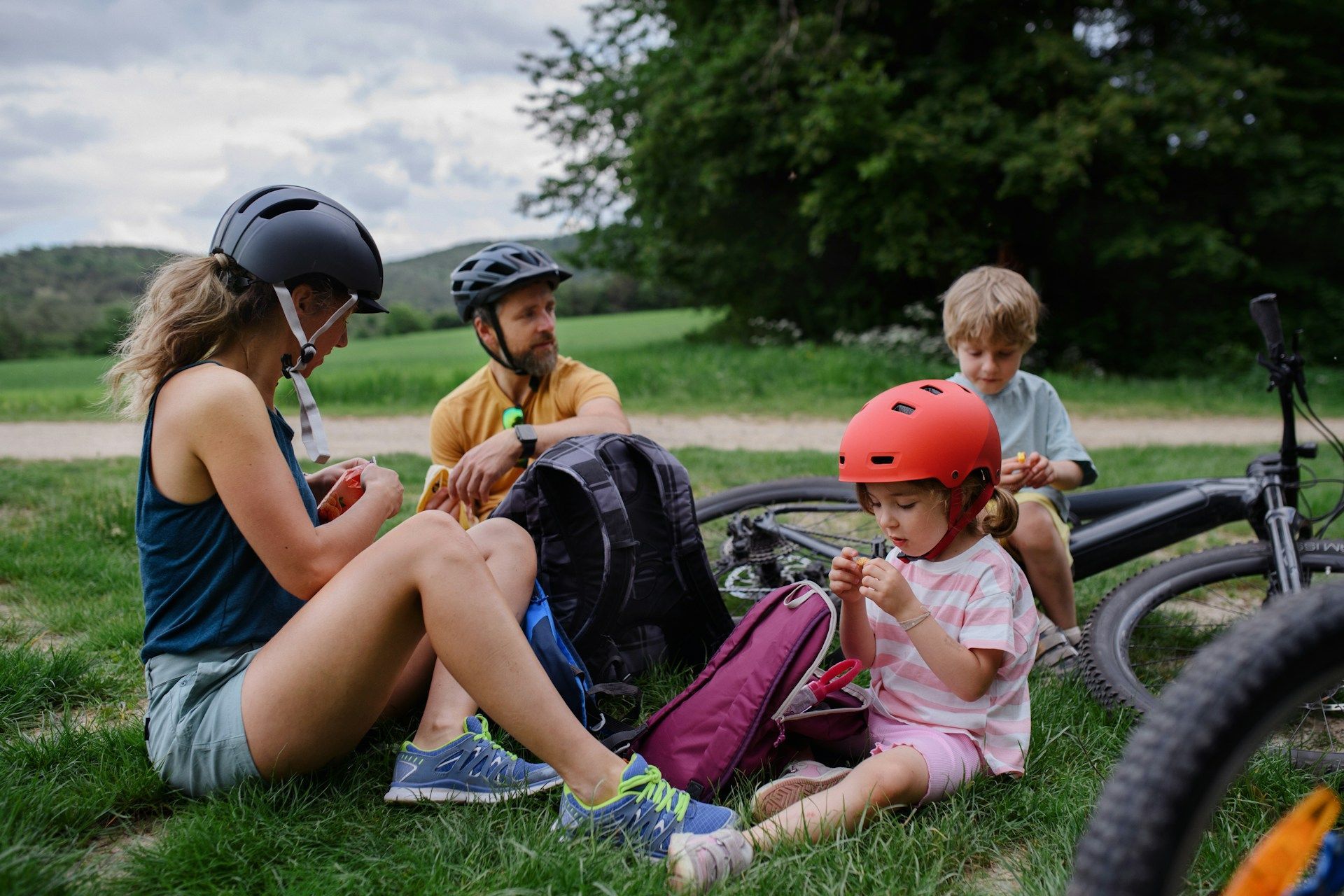 A family is sitting on the grass next to a bicycle.